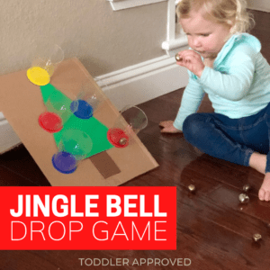 toddler throwing a jingle ball into a cup